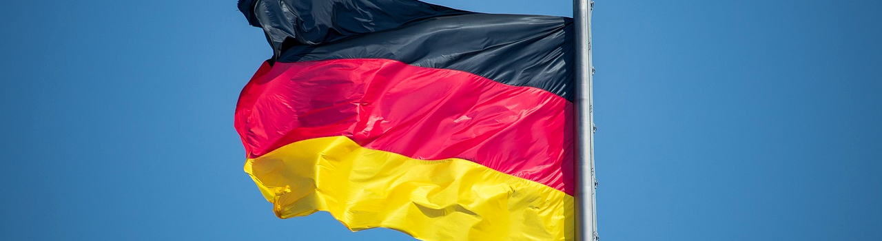 Im Wind wehende Fahne von Deutschland vor blauem Hintergrund