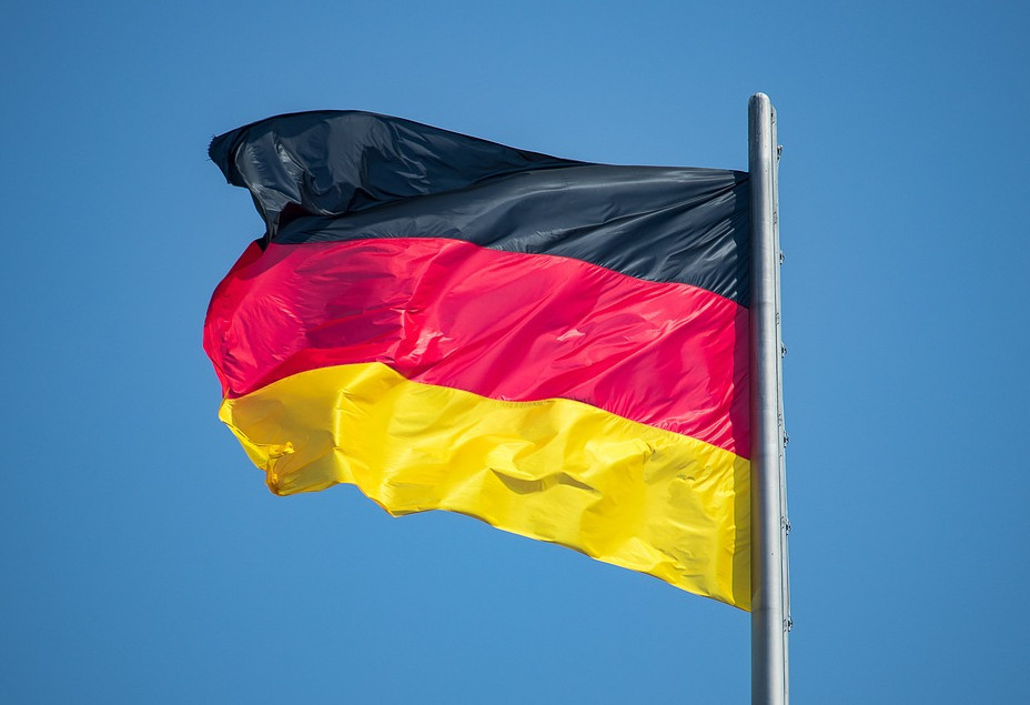 Im Wind wehende Fahne von Deutschland vor blauem Hintergrund