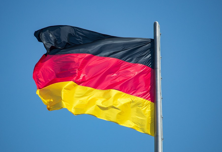 Im Wind wehende Fahne von Deutschland vor blauem Hintergrund