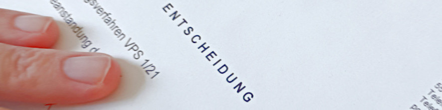 Finger und eine Brille liegen auf einem Blatt Papier, welches den Schriftzug Entscheidung trägt.