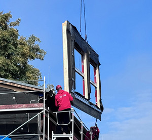 Montage eines vorgefertigten Fassadenelements an der Schulturnhalle in Körperich